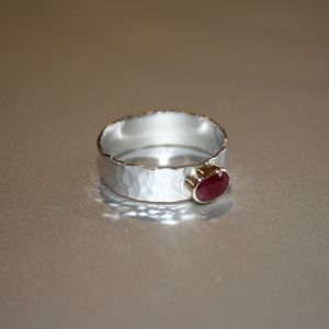 Silver hammered ring set with a ruby in gold bezel surround