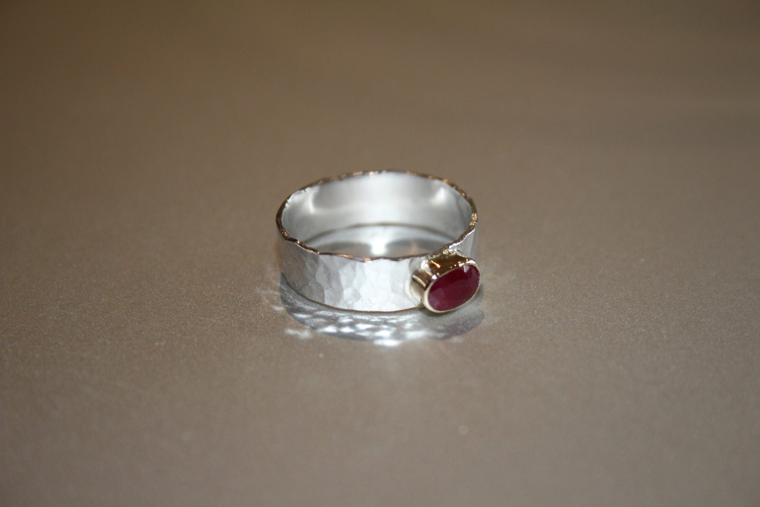 Silver hammered ring set with a ruby in gold bezel surround